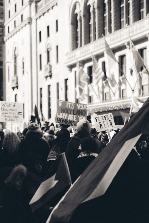 Free A black and white photo of a crowded protest with flags and signs in an urban setting. Stock Photo
