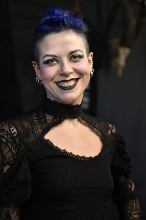 A woman with blue hair and black dress smiling