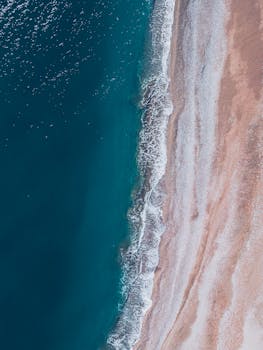 Stunning aerial view of turquoise waves and sandy beach in Demre, Antalya, showcasing summer's beauty.