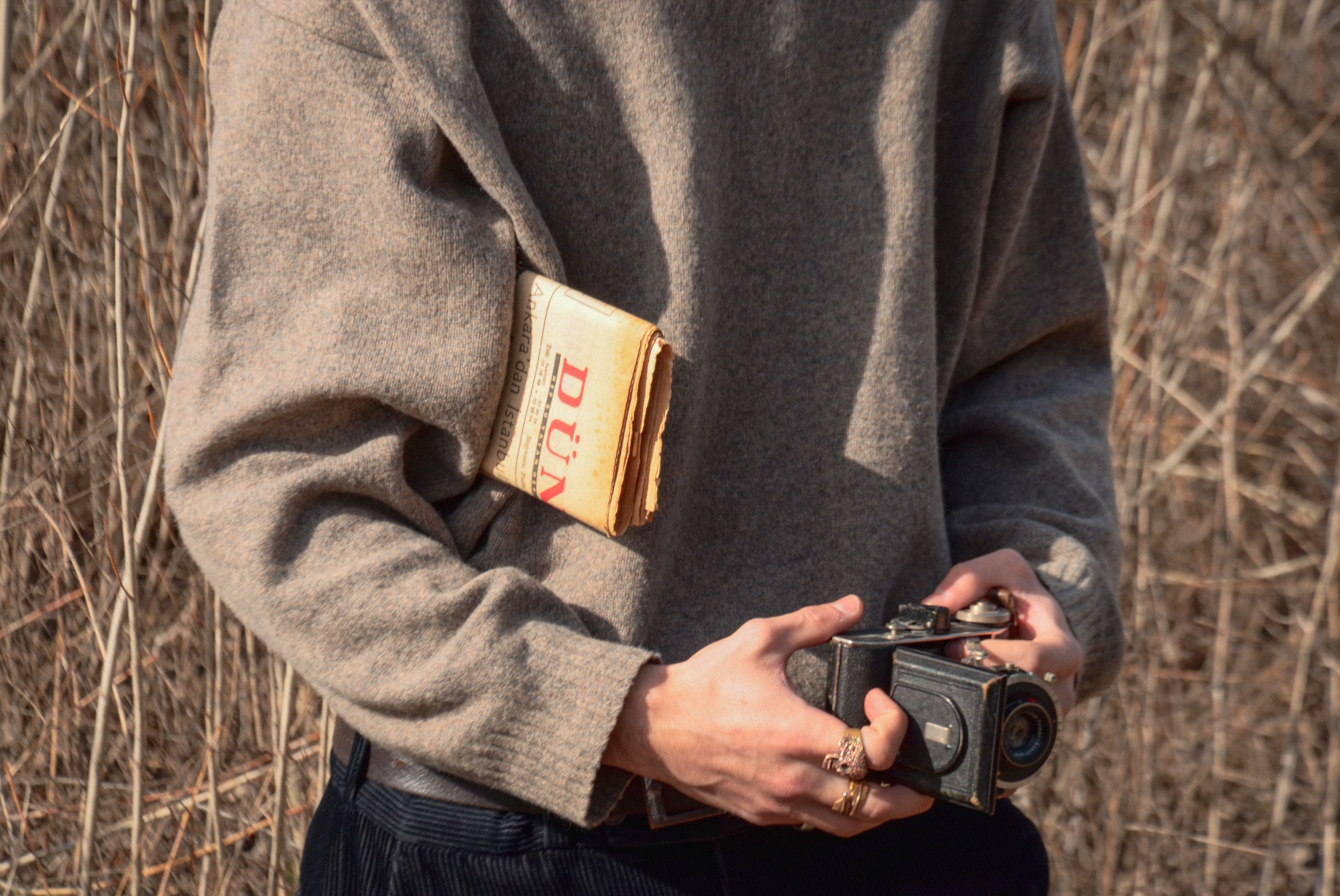 Hands holding a vintage sweater while photographing it with a smartphone to list for resale