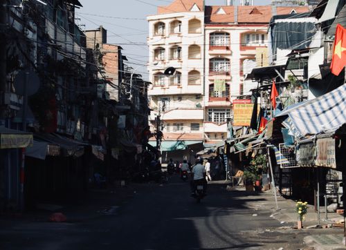 Free A lively street scene in Vietnam featuring buildings and vendors under clear daylight. Stock Photo