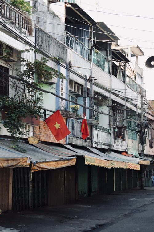 Free Rustic urban street with Vietnamese flags and balconies in the afternoon light. Stock Photo