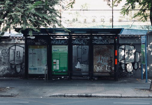 Deserted urban bus stop with graffiti art on city streets, featuring moody atmosphere.