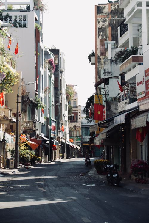 Free A vibrant Vietnamese street scene featuring flags and residential architecture on a sunny summer day. Stock Photo