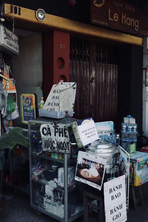 Free Street food stall offering Bánh Bao and Cà Phê in urban Vietnam scene. Stock Photo