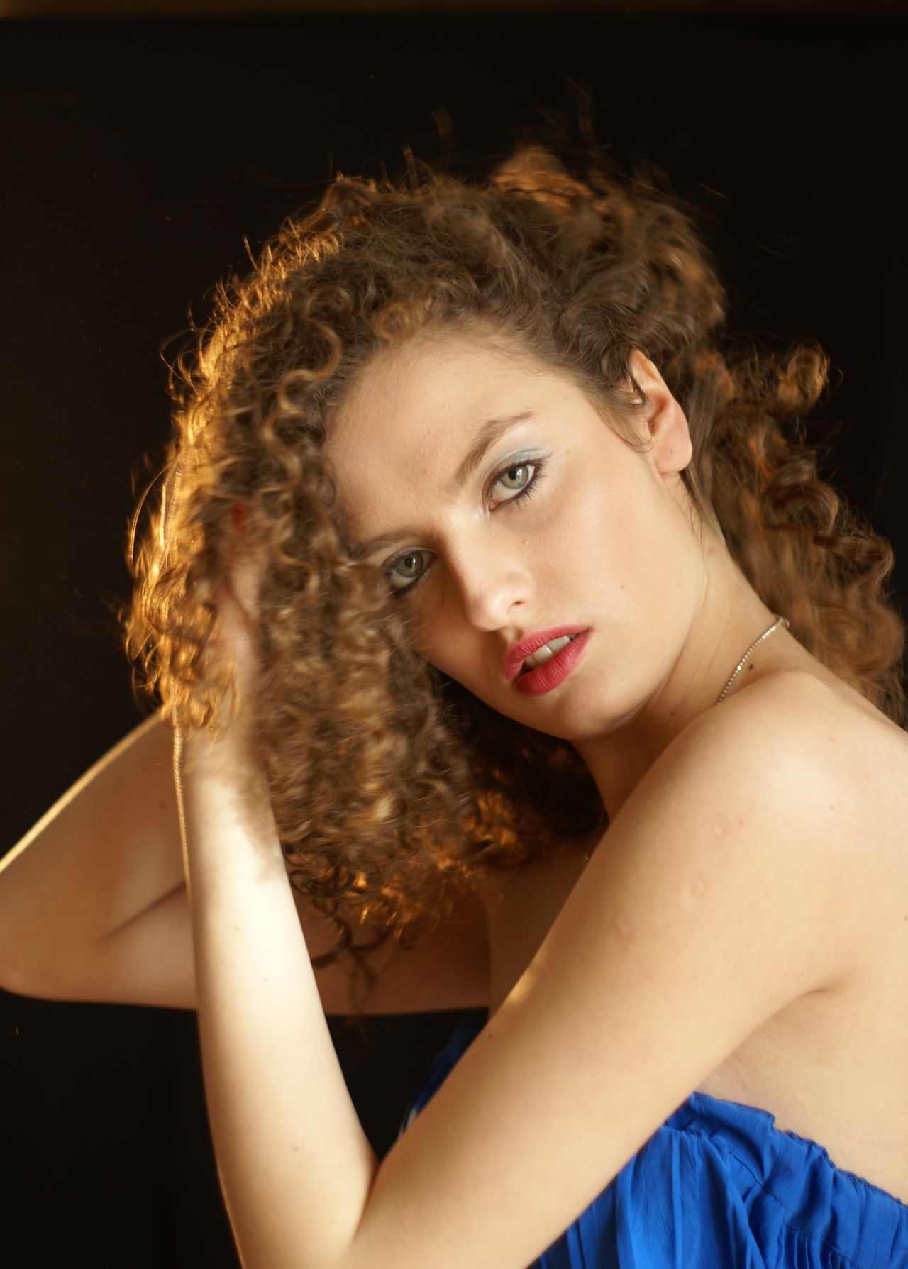 Woman with a chin-length curly bob and curly bangs in a studio portrait