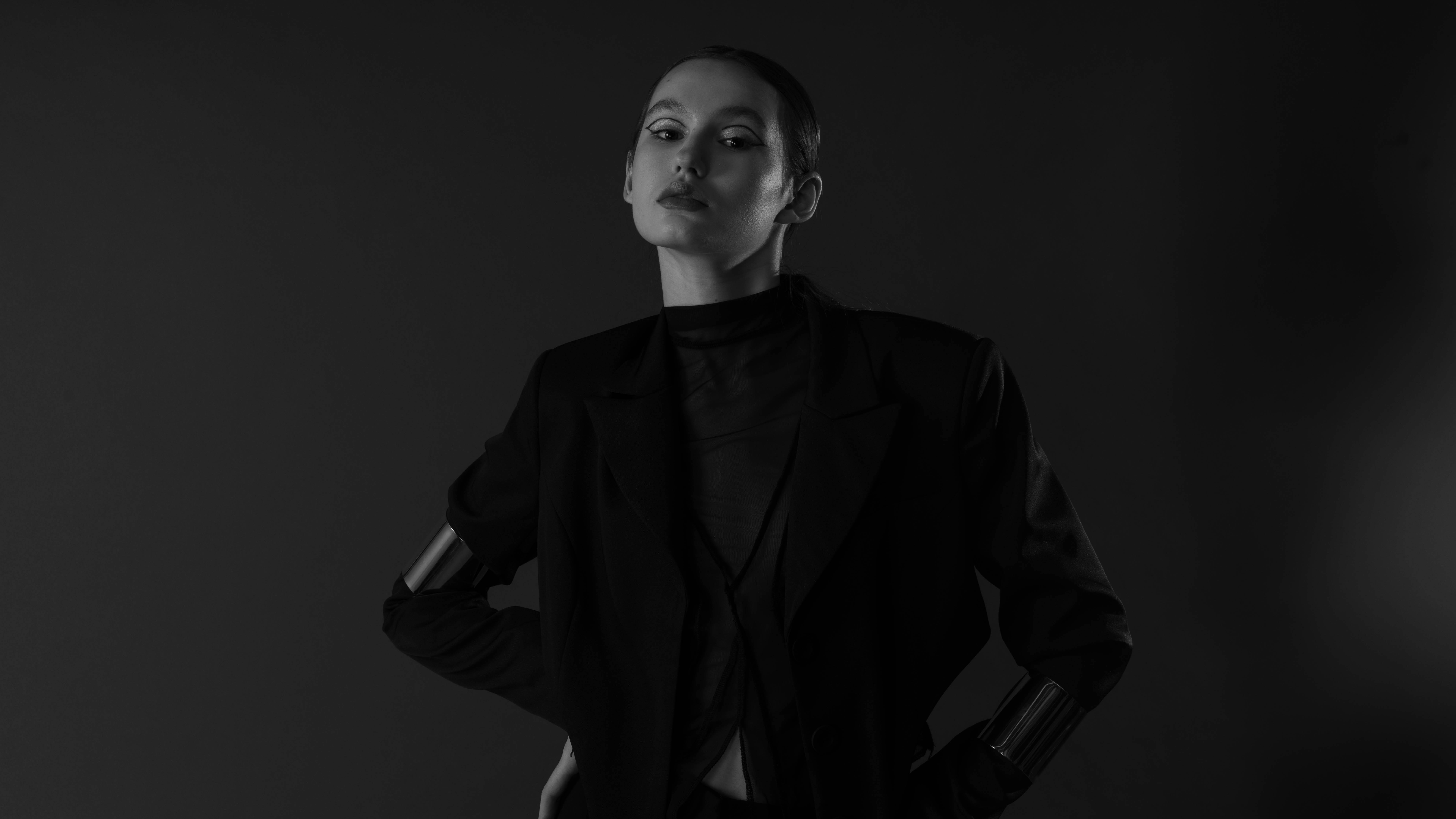 Free Monochrome fashion portrait showcasing a confident woman with hands on hips in a studio. Stock Photo