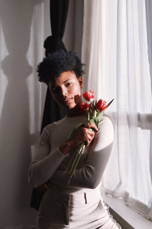 Woman Standing with Flowers by Window