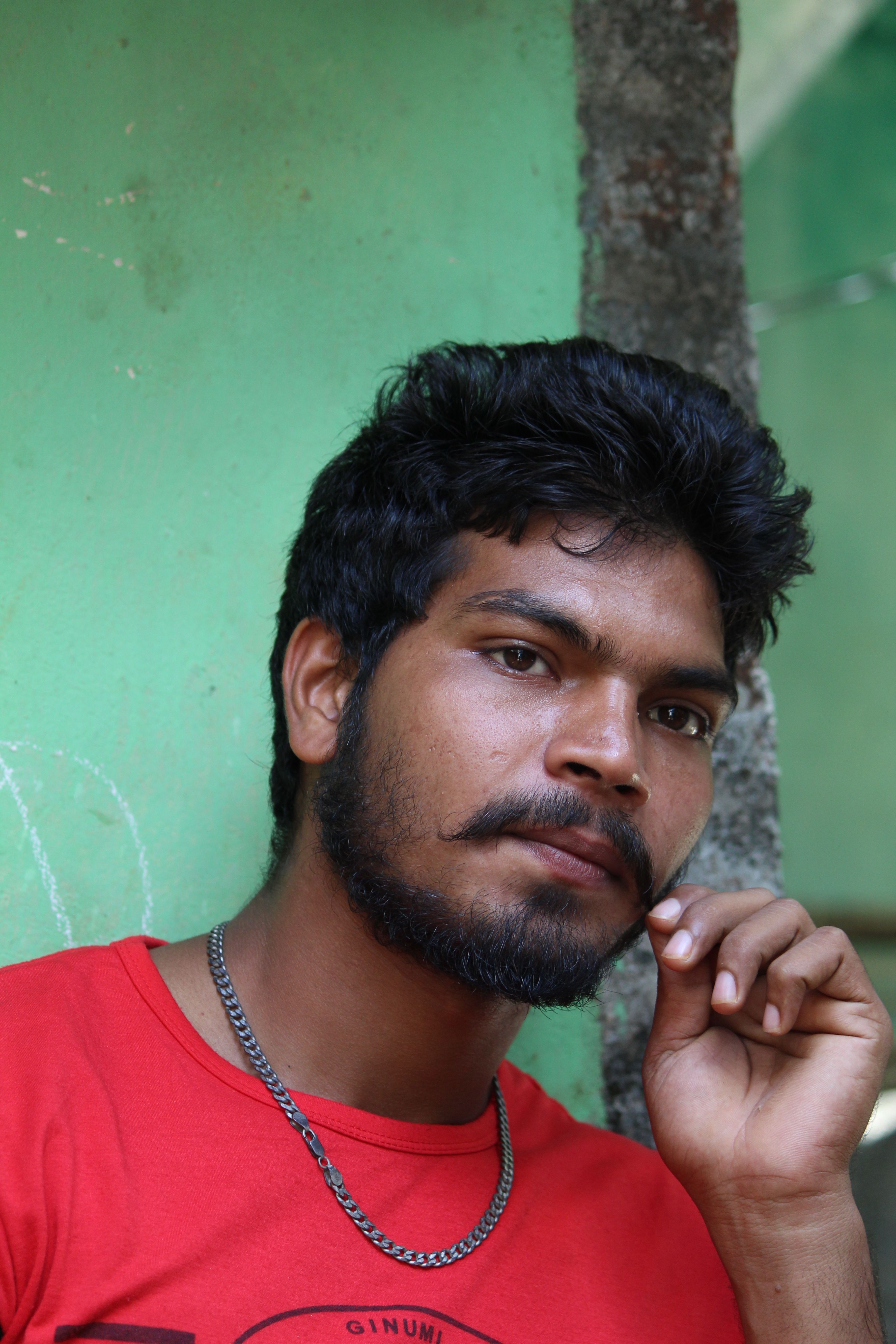 Portrait of a thoughtful man with facial hair against a green wall.
