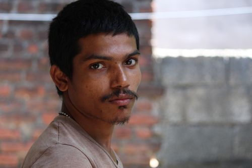 Free Close-up portrait of a young man with facial hair and mustache against a brick wall background. Stock Photo