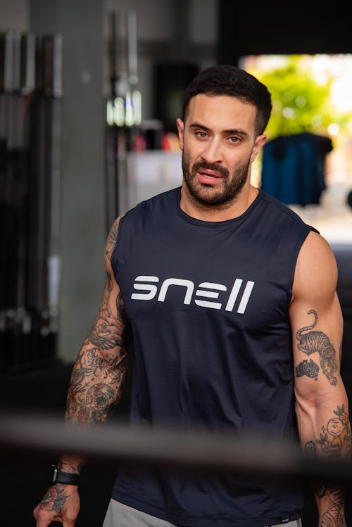 Free A man with tattoos standing in a gym Stock Photo