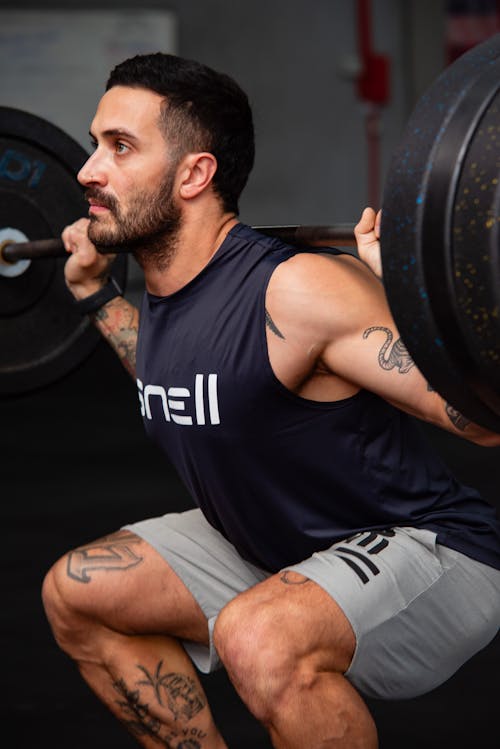 Free A man squatting with a barbell in his hands Stock Photo