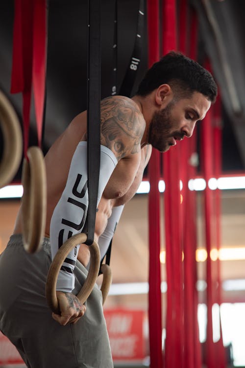 Free A man with tattoos on his arms is doing pull ups Stock Photo