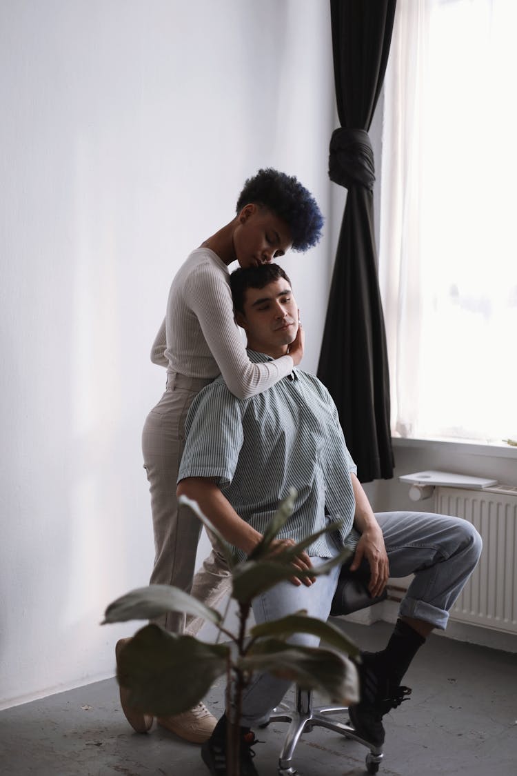 Woman Embracing A Man Sitting On A Chair