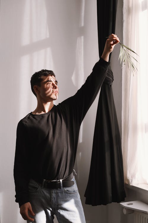 Man Standing with Arm Raised near Curtain
