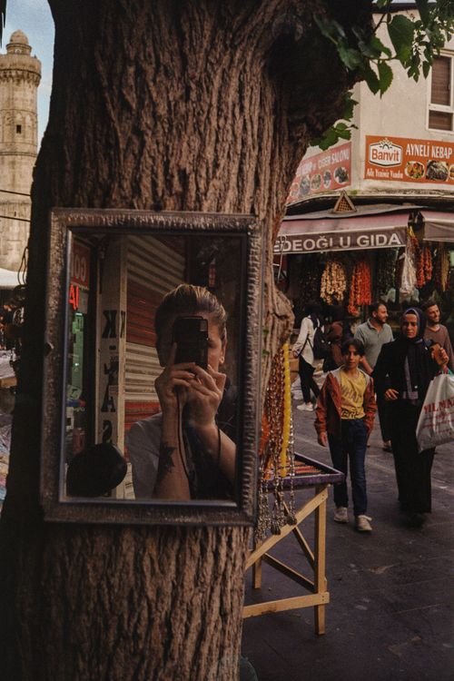 Free Photo captures a bustling street market reflected in a tree-hung mirror. Stock Photo