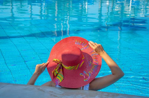 A Woman Wearing a Sunhat Sitting in a Swimming Pool 