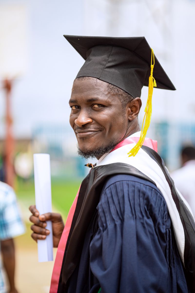 A smiling international graduate holding their diploma after finishing their degree