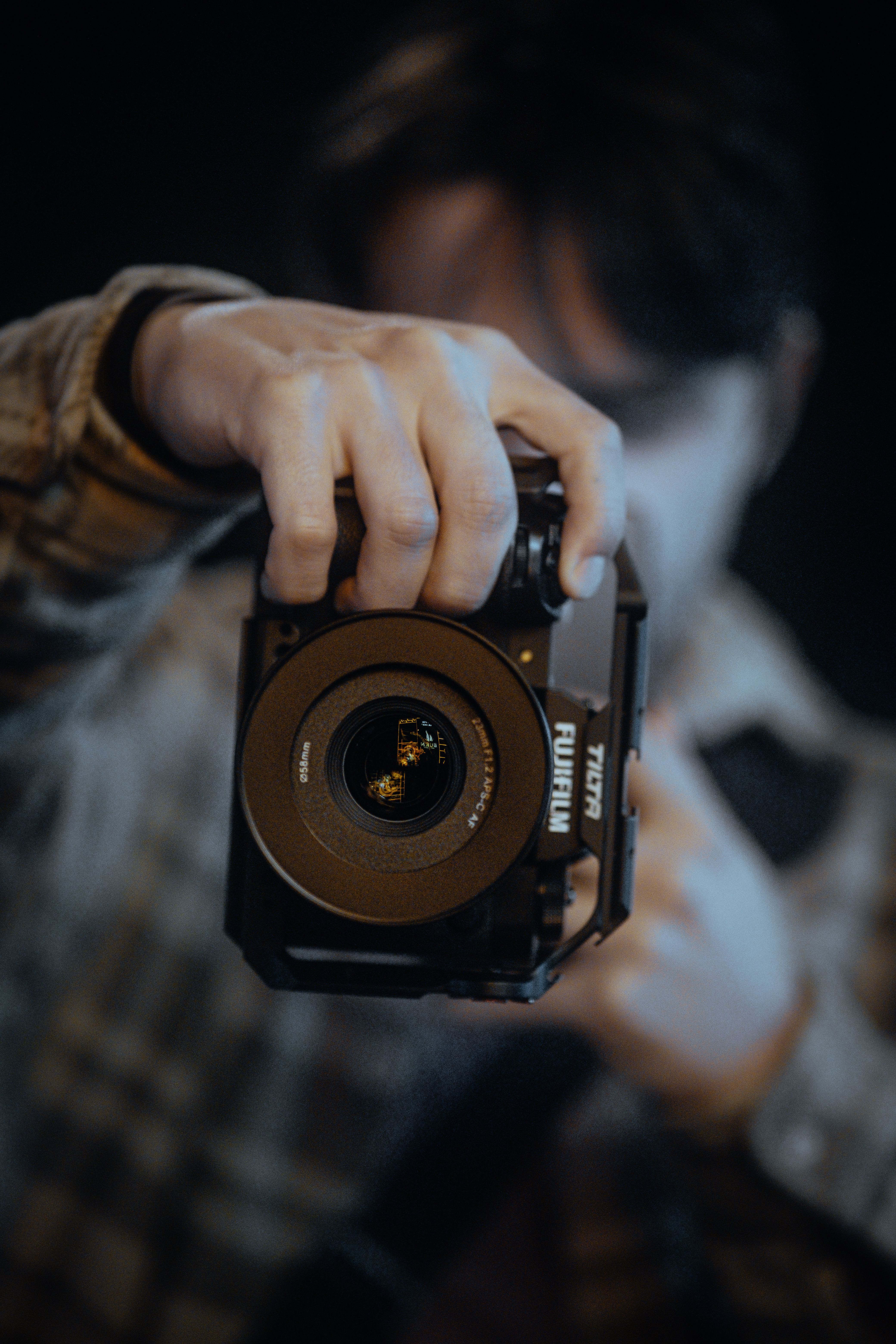 A male adult holding a camera with a full cage in a focused shot.