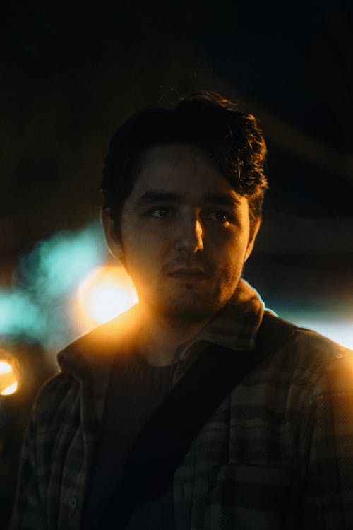 A man standing in the dark with a street light in the background
