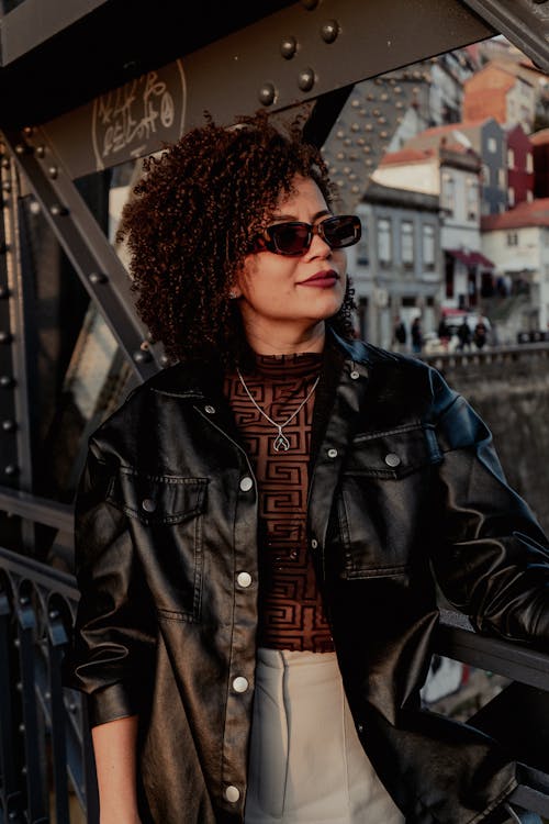A woman in sunglasses and a leather jacket on a bridge