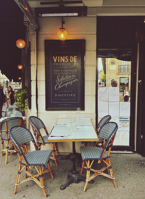 Free Cozy Parisian café terrace with vintage chairs and tables, perfect for an alfresco dining experience. Stock Photo
