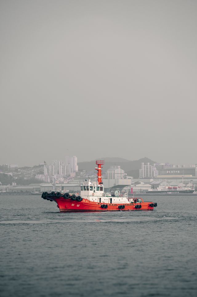 Vessel sailing through an urban harbor with cityscape backdrop