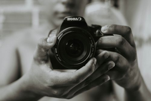 Free Black and white close-up of hands holding a Canon camera, focusing on photography. Stock Photo