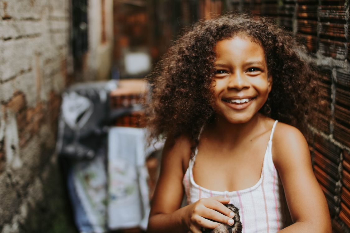 Girl with Brown Curly Hair Smiling on a Yard · Free Stock Photo