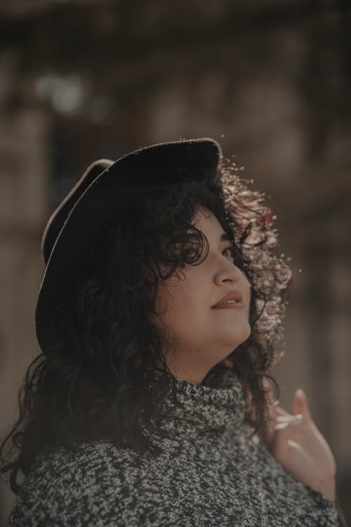 A woman with curly hair wearing a hat