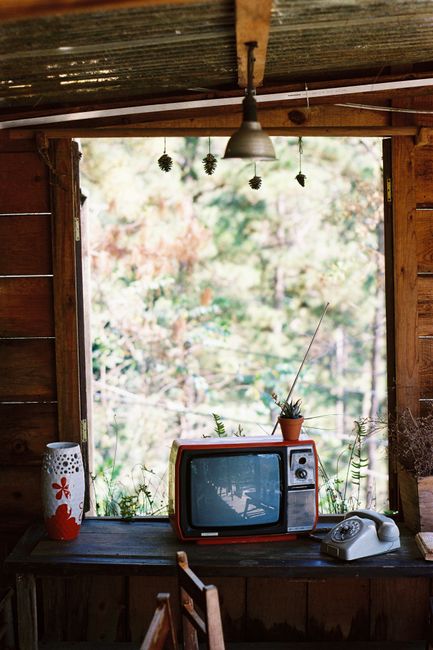 Cozy room with vintage TV and rotary phone by a window, reflecting a nostalgic ambiance.