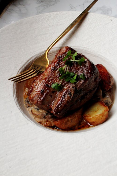 Roast Dish with a Golden Fork on a White Plate