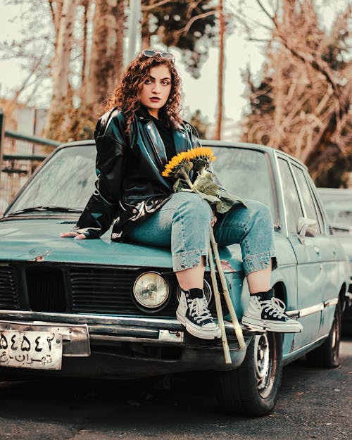 Woman Sitting on a Vintage Car with Sunflowers