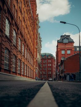 Low-angle view of a city street featuring vibrant red brick buildings against a blue sky.
