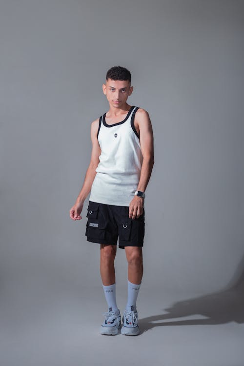 A young man in shorts and tank top posing