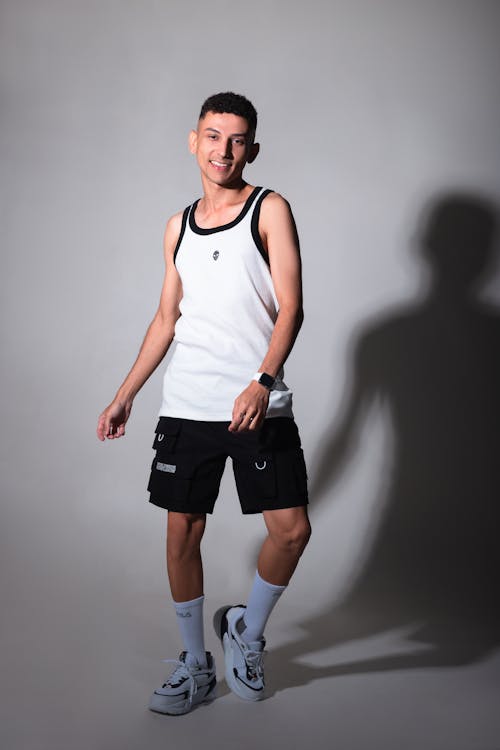 A young man in black shorts and white tank top