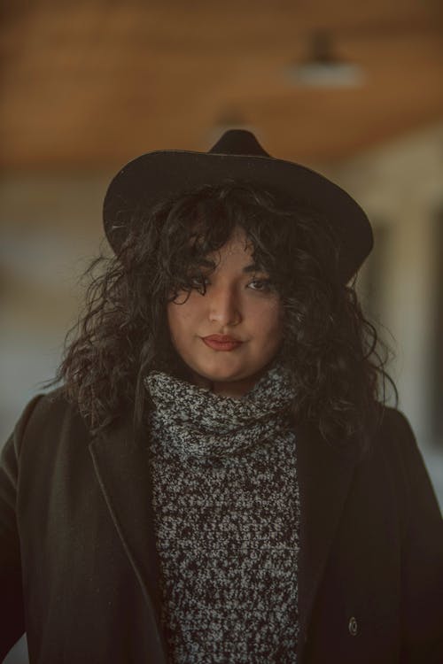 A woman with curly hair wearing a hat and sweater