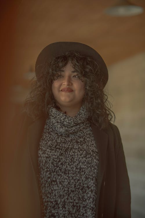 A woman with curly hair and a hat