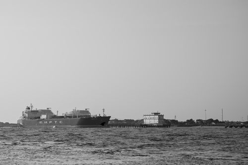 Free Elegant black and white shot of a cargo ship near the coast with a clear sky. Stock Photo