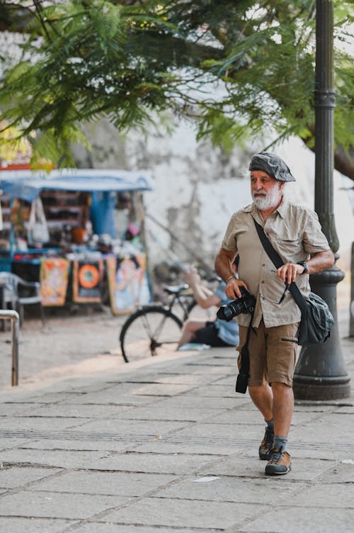 An older man walking down the street with a camera