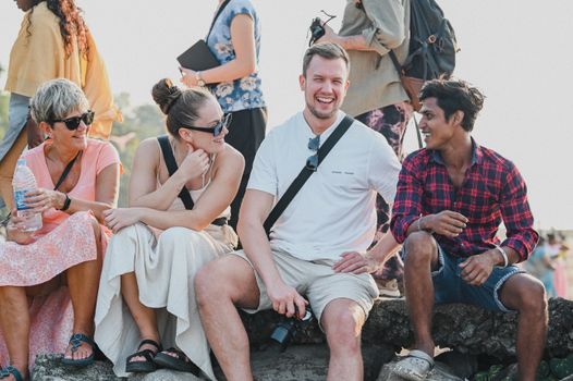 A diverse group of friends laughing and enjoying a sunny day outdoors, captured in candid moment.