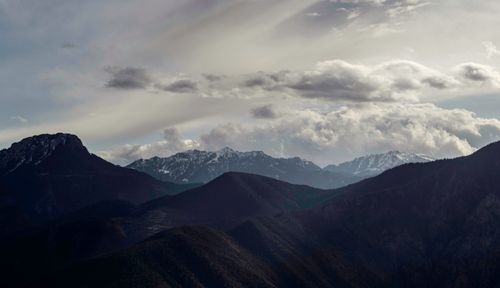 Free Dramatic clouds over a snowcapped mountain range creating a stunning landscape view. Stock Photo
