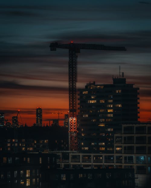 Construction Crane over Buildings in City at Sunset