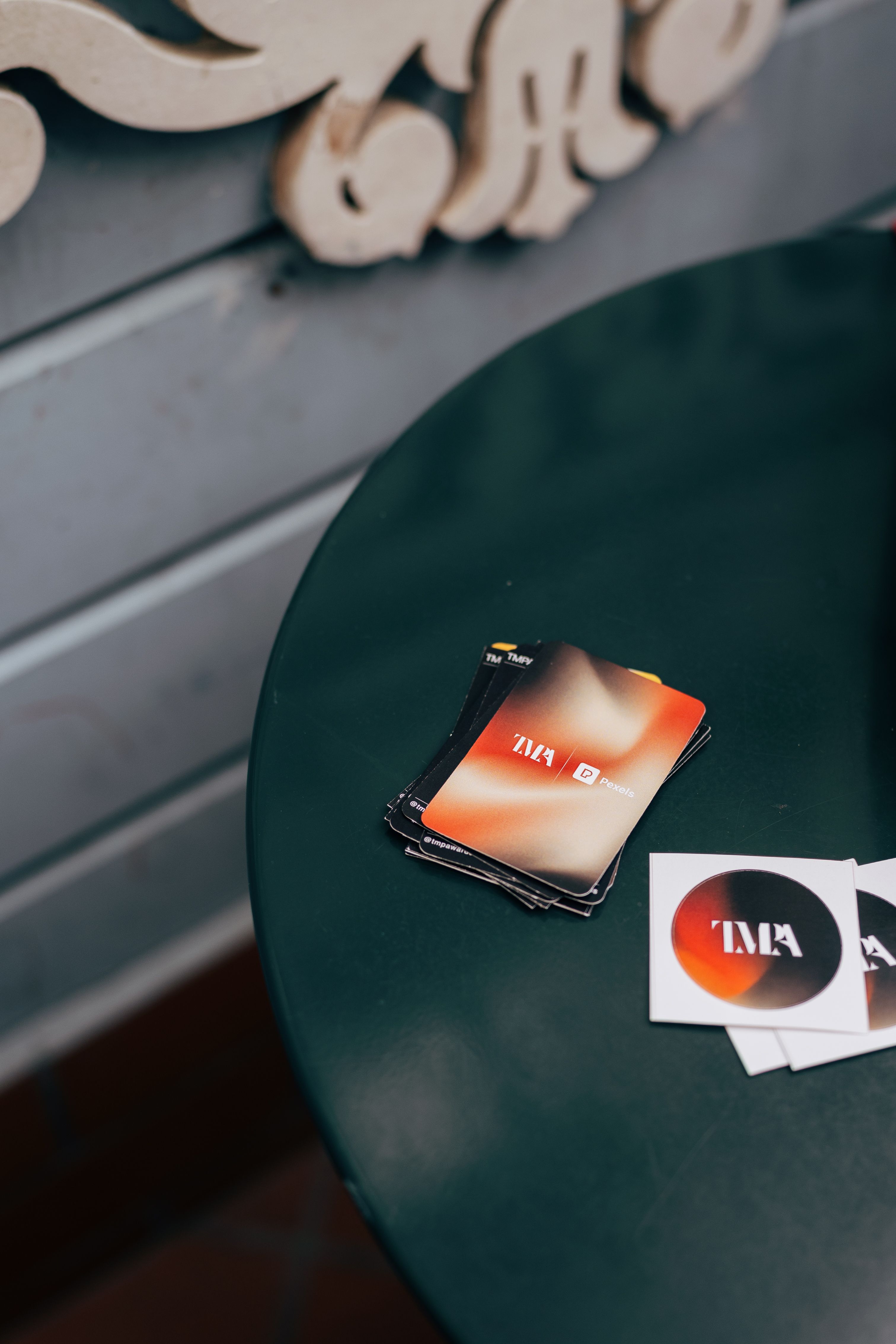 Colorful business cards displayed creatively on a dark green round table with artistic decoration.