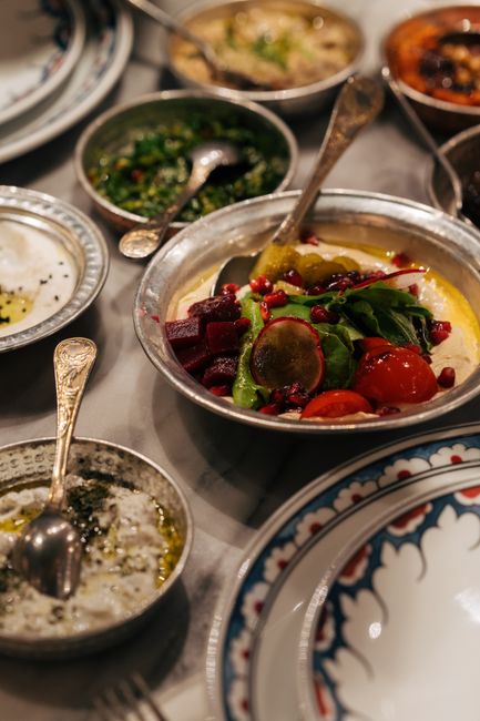 A beautifully arranged Middle Eastern meal featuring vibrant salads and dips in ornate bowls.