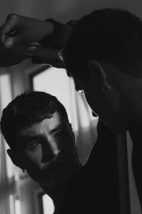 Black and White Photo of a Man Looking at His Mirror Reflection 