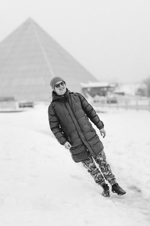 portrait of a young man in winter during a free fall against the background of a pyramid-shaped shopping center in Vitebsk