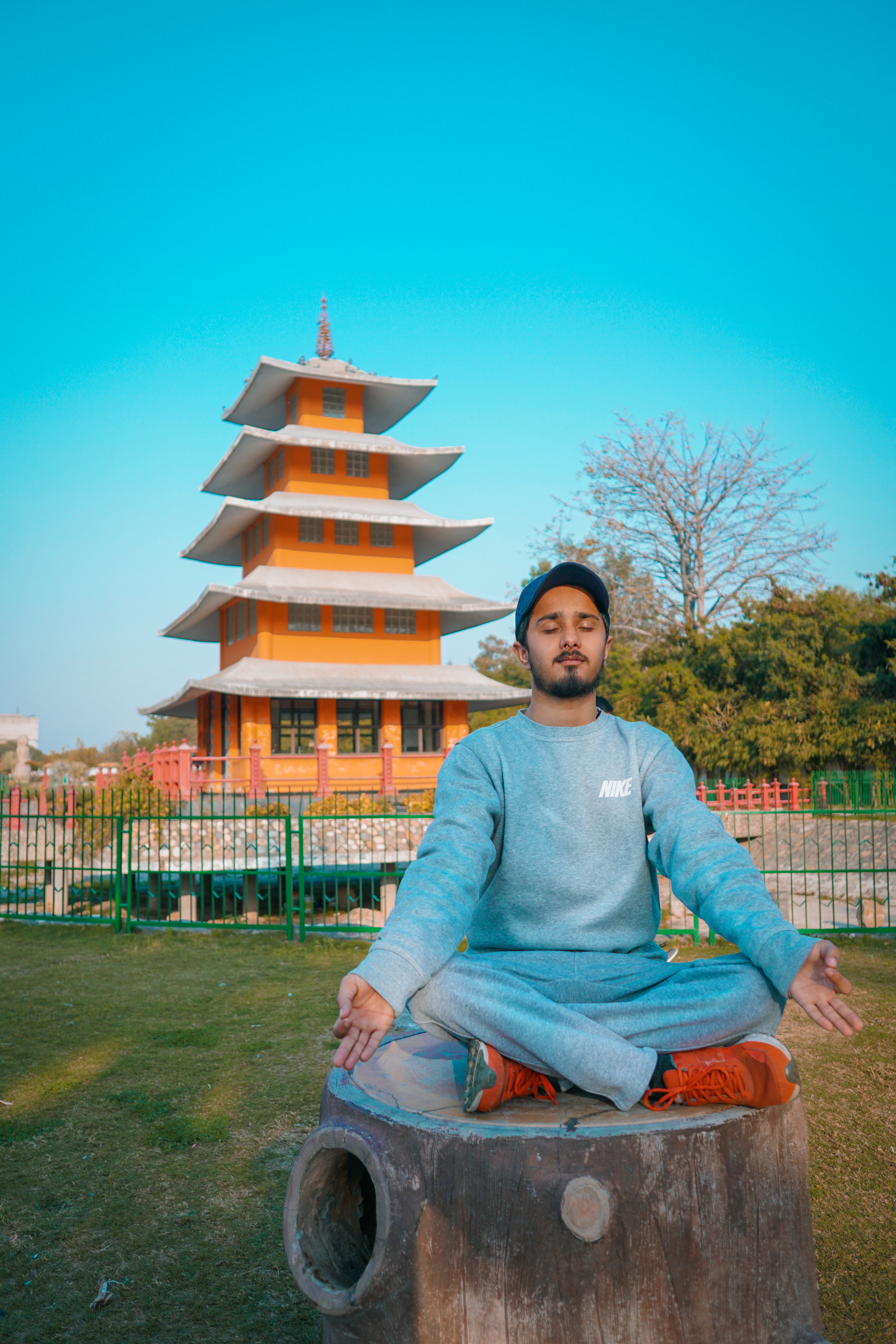 A man meditates on a tree stump in a serene Japanese garden, embodying tranquility and mindfulness.