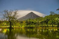 宁静的夜晚，火山倒映在星光灿烂的天空下平静的湖水中