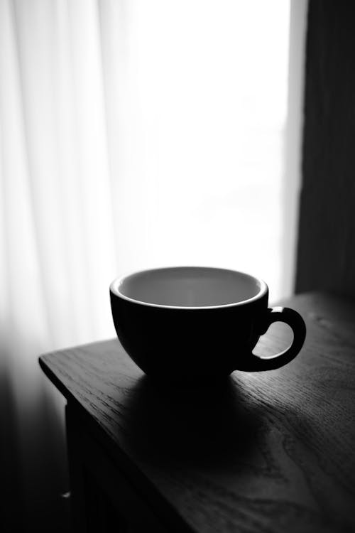 A black and white photo of a cup on a table